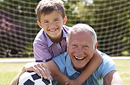 Old man playing soccer with young boy